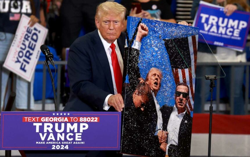 Republican presidential nominee former president Donald Trump holds an artwork of the assassination attempt, which he signed for the artist, during a campaign rally at the Georgia State University Convocation Center on August 3, in Atlanta.