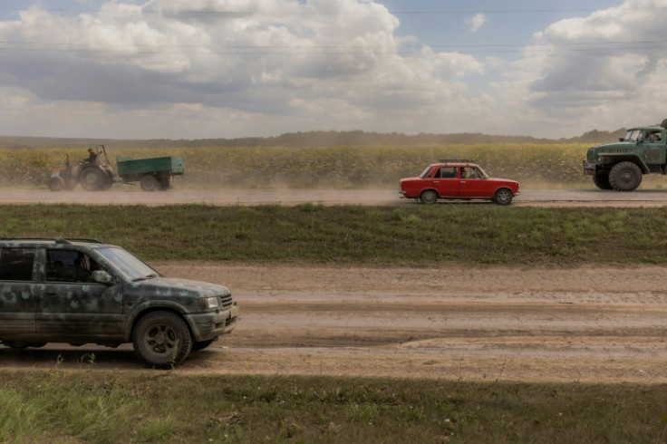 Ukrainian military vehicles and civilian cars drive past near the border with Russia