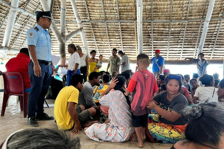 Voters wait to cast their ballot at a polling station in Kiribati under the gaze of a policeman