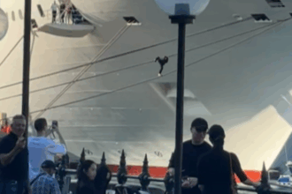 Crowd watches as man climbs cruise ship ropes at Circular Quay