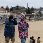 People walking with umbrellas at Bondi Beach during stormy weather
