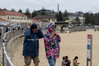 People walking with umbrellas at Bondi Beach during stormy weather