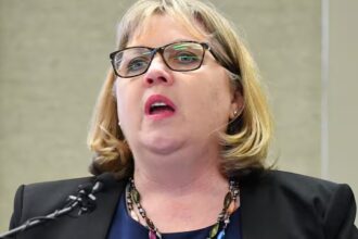Australian Education Union president speaking at a lectern during a press conference on Gaza conflict guidelines.