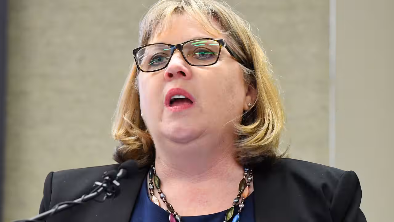 Australian Education Union president speaking at a lectern during a press conference on Gaza conflict guidelines.
