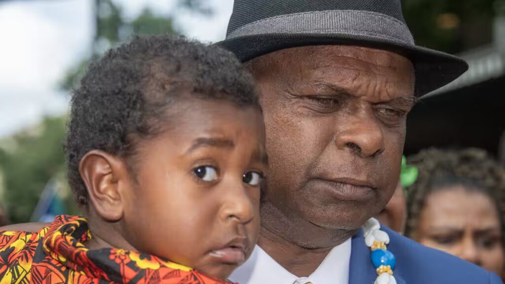 Uncle Pabai Pabai carries a child outside the Federal Court of Australia in Cairns on Tuesday. (AAP Image/Brian Cassey) Source: AAP / BRIAN CASSEY/AAPIMAGE