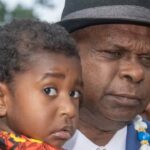 Uncle Pabai Pabai carries a child outside the Federal Court of Australia in Cairns on Tuesday. (AAP Image/Brian Cassey) Source: AAP / BRIAN CASSEY/AAPIMAGE