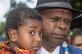 Uncle Pabai Pabai carries a child outside the Federal Court of Australia in Cairns on Tuesday. (AAP Image/Brian Cassey) Source: AAP / BRIAN CASSEY/AAPIMAGE