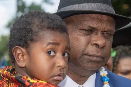 Uncle Pabai Pabai carries a child outside the Federal Court of Australia in Cairns on Tuesday. (AAP Image/Brian Cassey) Source: AAP / BRIAN CASSEY/AAPIMAGE