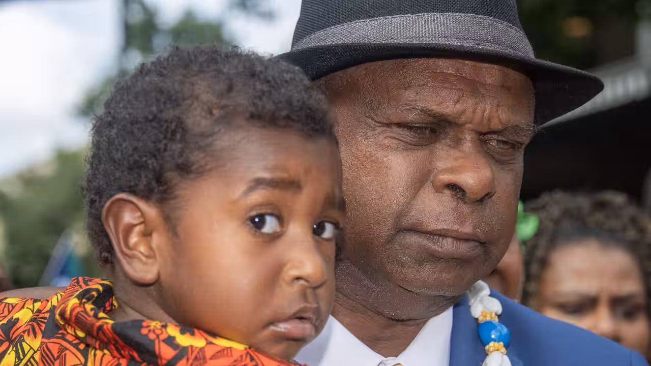 Uncle Pabai Pabai carries a child outside the Federal Court of Australia in Cairns on Tuesday. (AAP Image/Brian Cassey) Source: AAP / BRIAN CASSEY/AAPIMAGE